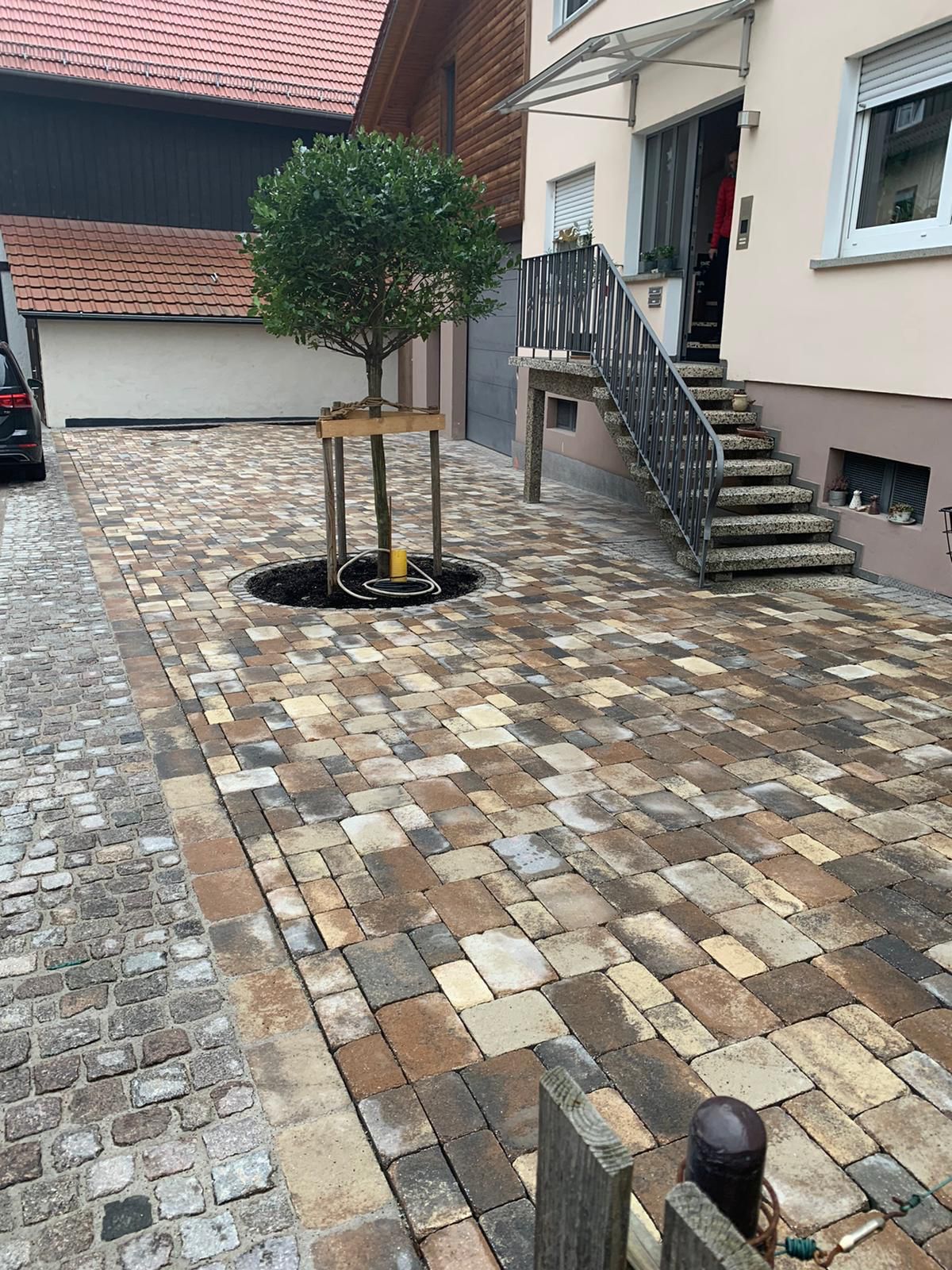 Verlegung von Pflaster und Schachtabdeckung mit Natursteinen integriert.